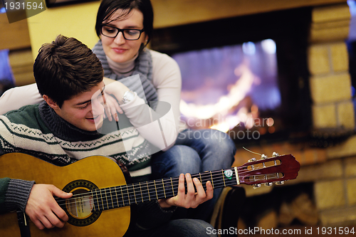 Image of Young romantic couple relax on sofa in front of fireplace at hom