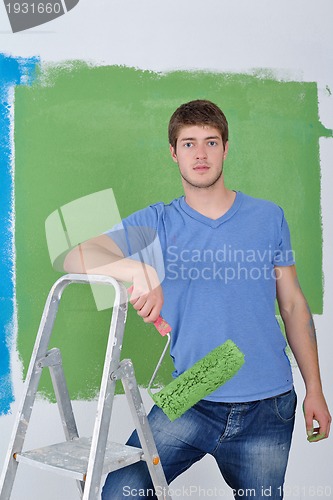 Image of handsome young man paint white wall in color