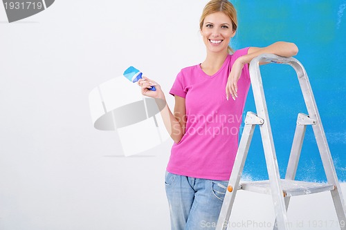 Image of happy smiling woman painting interior of house