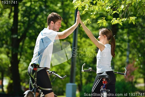 Image of Happy couple riding bicycle outdoors
