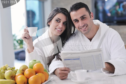 Image of Happy couple reading the newspaper in the kitchen at breakfast