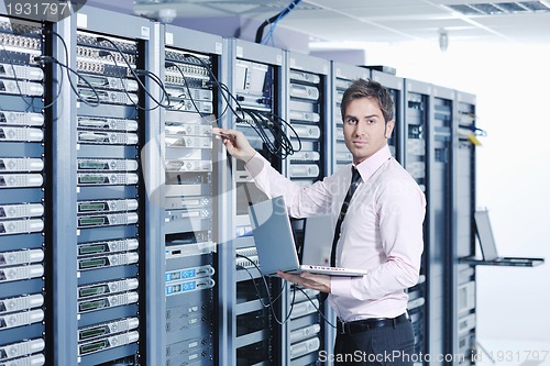 Image of businessman with laptop in network server room