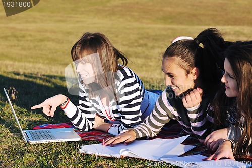 Image of group of teens working on laptop outdoor