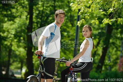 Image of Happy couple riding bicycle outdoors