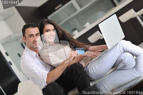 Image of joyful couple relax and work on laptop computer at modern home