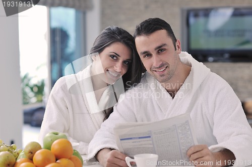 Image of Happy couple reading the newspaper in the kitchen at breakfast