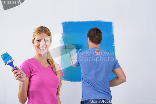 Image of happy couple paint wall at new home