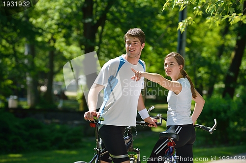 Image of Happy couple riding bicycle outdoors