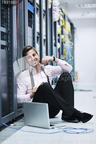 Image of businessman with laptop in network server room