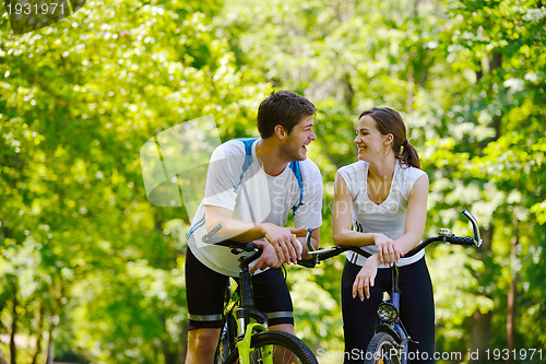 Image of Happy couple riding bicycle outdoors