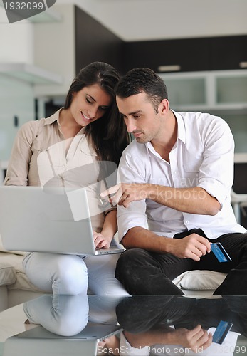 Image of joyful couple relax and work on laptop computer at modern home