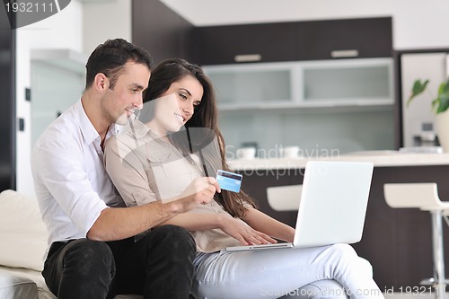 Image of joyful couple relax and work on laptop computer at modern home