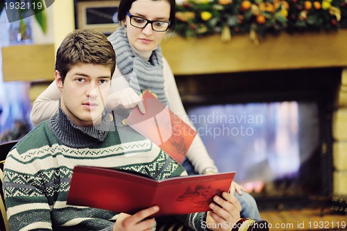 Image of Young romantic couple sitting and relaxing in front of fireplace
