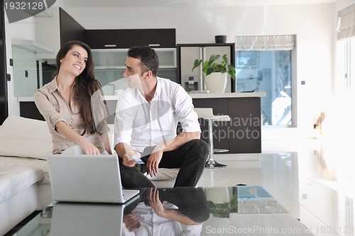 Image of joyful couple relax and work on laptop computer at modern home