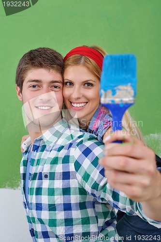 Image of happy couple paint wall at new home