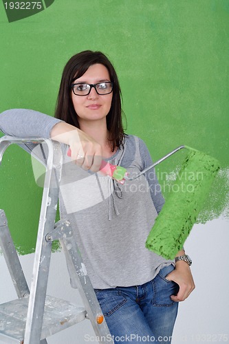 Image of happy smiling woman painting interior of house