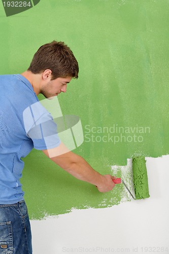 Image of handsome young man paint white wall in color