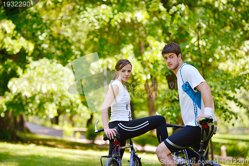 Image of Happy couple riding bicycle outdoors