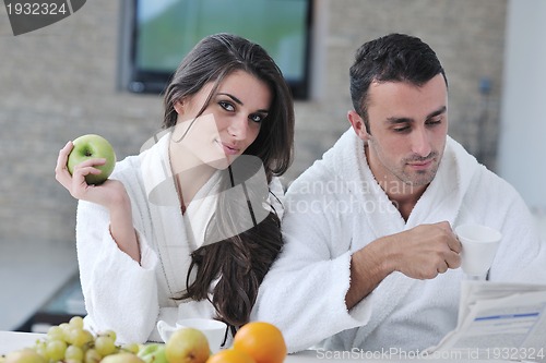 Image of Happy couple reading the newspaper in the kitchen at breakfast