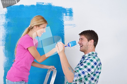 Image of happy couple paint wall at new home