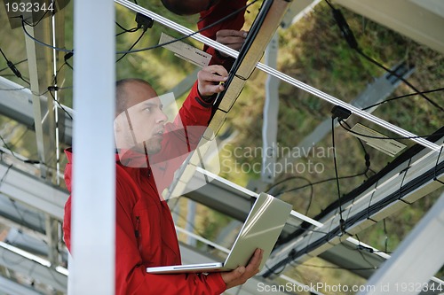 Image of engineer using laptop at solar panels plant field