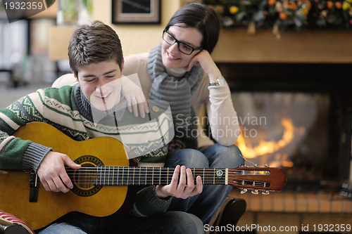 Image of Young romantic couple sitting on sofa in front of fireplace at h