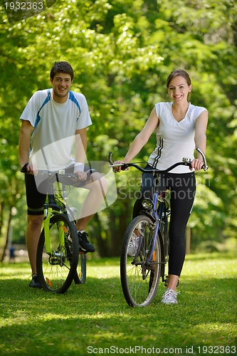 Image of Happy couple riding bicycle outdoors