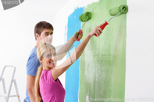 Image of happy couple paint wall at new home