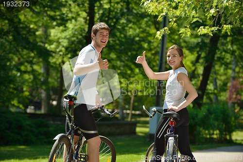 Image of Happy couple riding bicycle outdoors