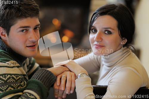 Image of Young romantic couple relax on sofa in front of fireplace at hom