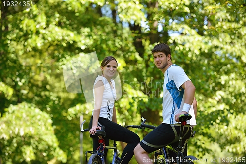 Image of Happy couple riding bicycle outdoors