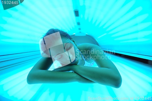 Image of Beautiful young woman tanning in solarium