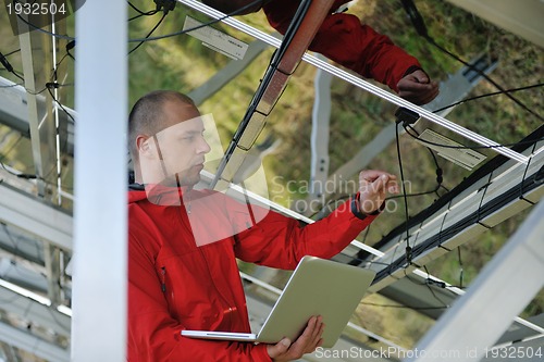 Image of engineer using laptop at solar panels plant field