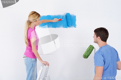 Image of happy couple paint wall at new home