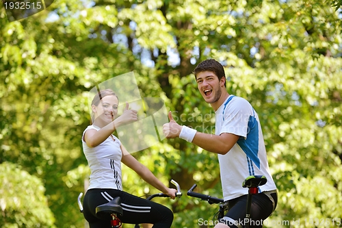 Image of Happy couple riding bicycle outdoors
