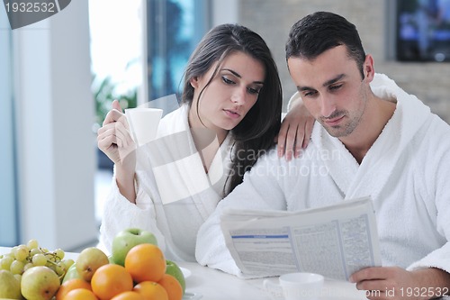 Image of Happy couple reading the newspaper in the kitchen at breakfast