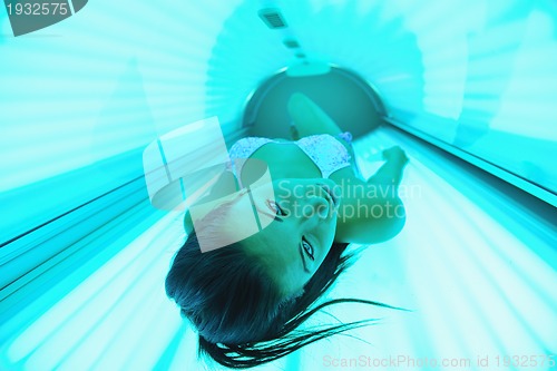 Image of Beautiful young woman tanning in solarium