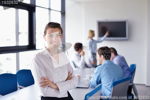 Image of business woman with her staff in background at office