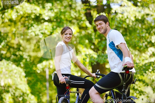 Image of Happy couple riding bicycle outdoors