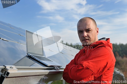 Image of engineer using laptop at solar panels plant field