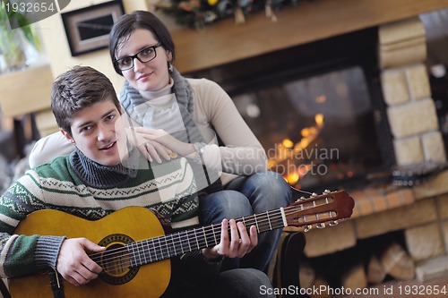 Image of Young romantic couple sitting and relaxing in front of fireplace