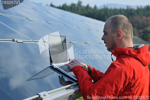 Image of engineer using laptop at solar panels plant field