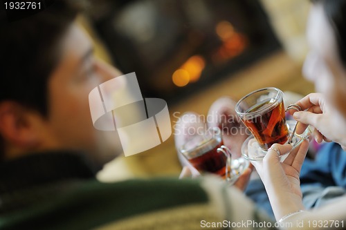 Image of Young romantic couple sitting and relaxing in front of fireplace
