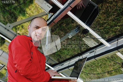 Image of engineer using laptop at solar panels plant field