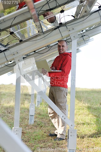 Image of engineer using laptop at solar panels plant field