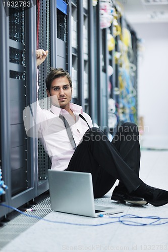 Image of businessman with laptop in network server room