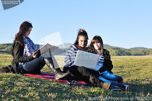 Image of group of teens working on laptop outdoor