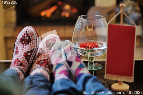Image of Young romantic couple sitting and relaxing in front of fireplace