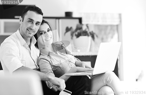 Image of joyful couple relax and work on laptop computer at modern home