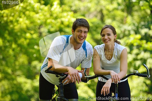 Image of Happy couple riding bicycle outdoors